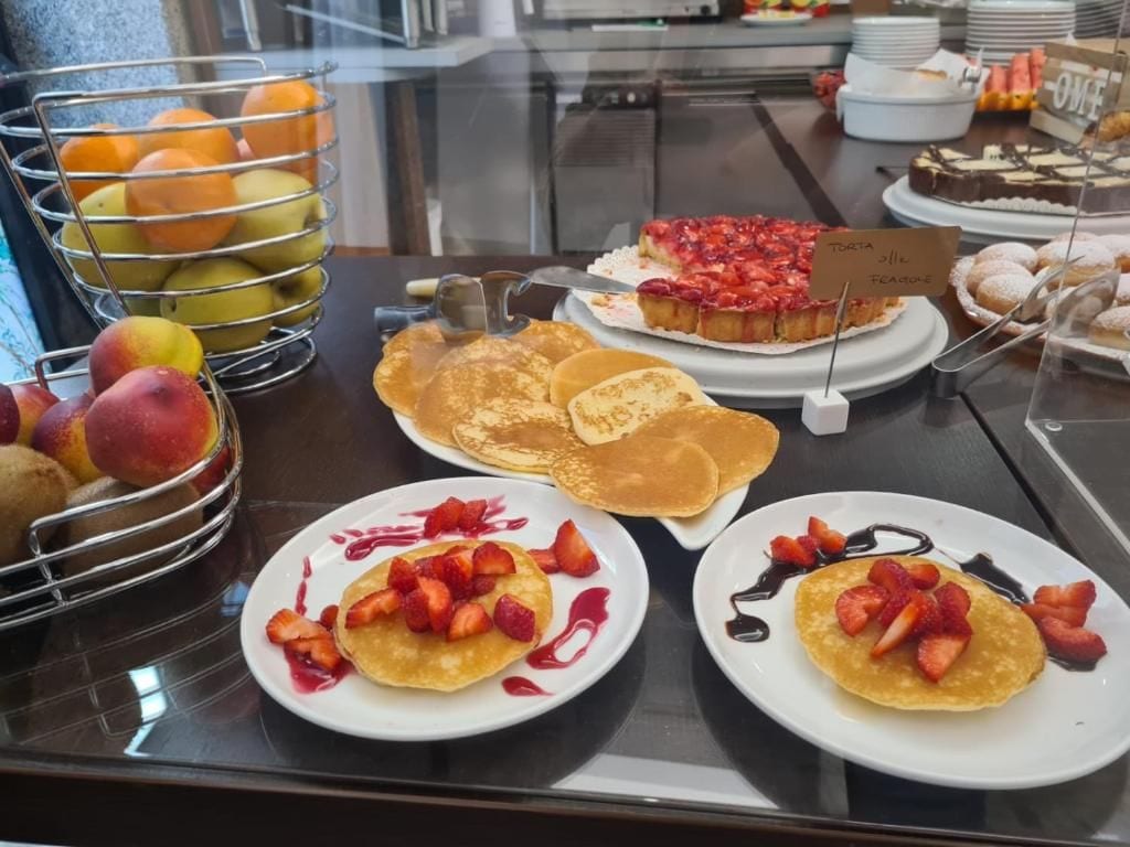A breakfast buffet with pancakes, fruit, and a cake.