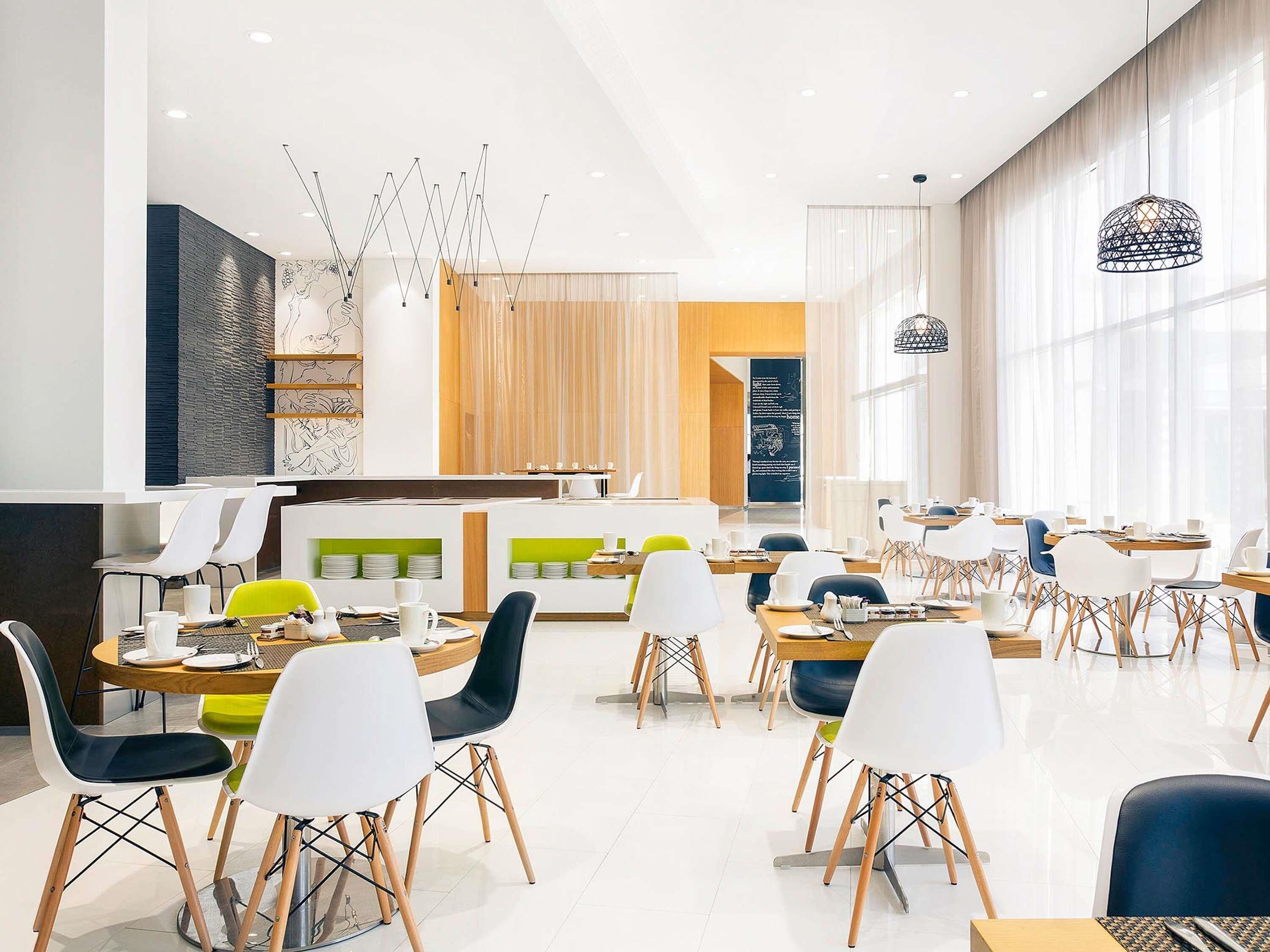 A modern dining area with tables and chairs, a counter, and a menu board.