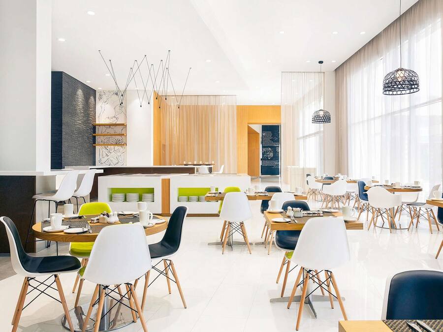 A modern dining area with tables and chairs, a counter, and a menu board.