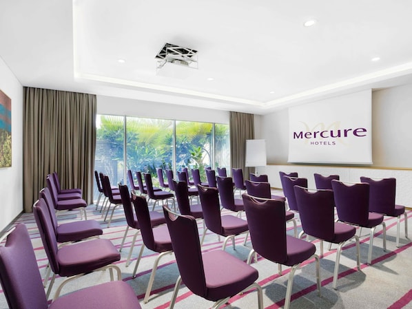 A conference room with purple chairs, a whiteboard, and a large window with a view of greenery. - Mercure Sohar (Sohar)