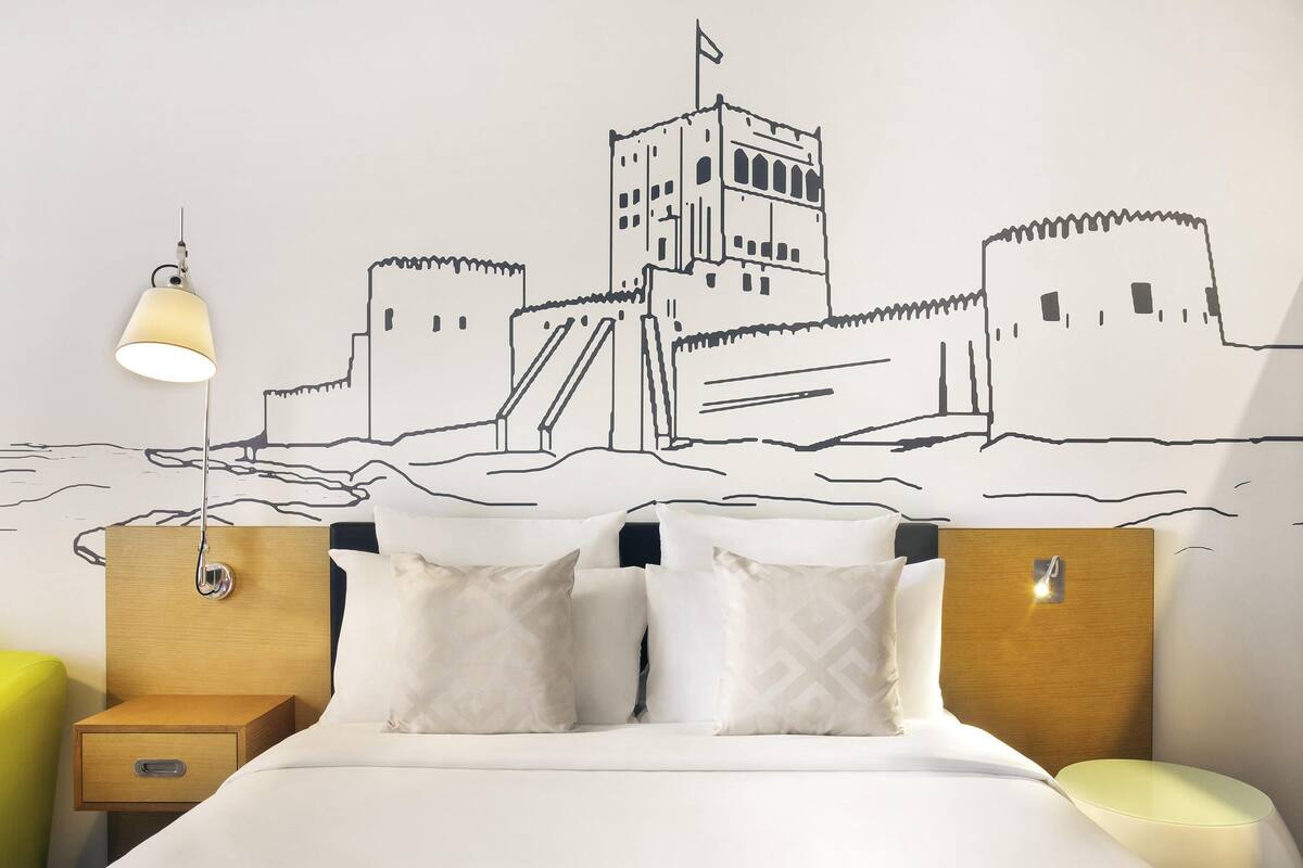 Una camera da letto con un letto, due comodini, un tavolino da notte e un affresco raffigurante un castello.
