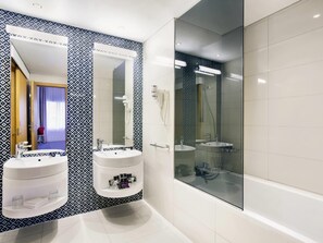 A modern bathroom with two sinks, a large mirror, and a glass-enclosed shower area. - Mercure Sohar (Sohar)
