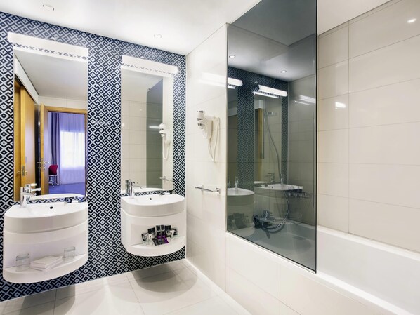 Un baño moderno con dos lavamanos, un espejo grande y cabina de ducha con paredes de vidrio.