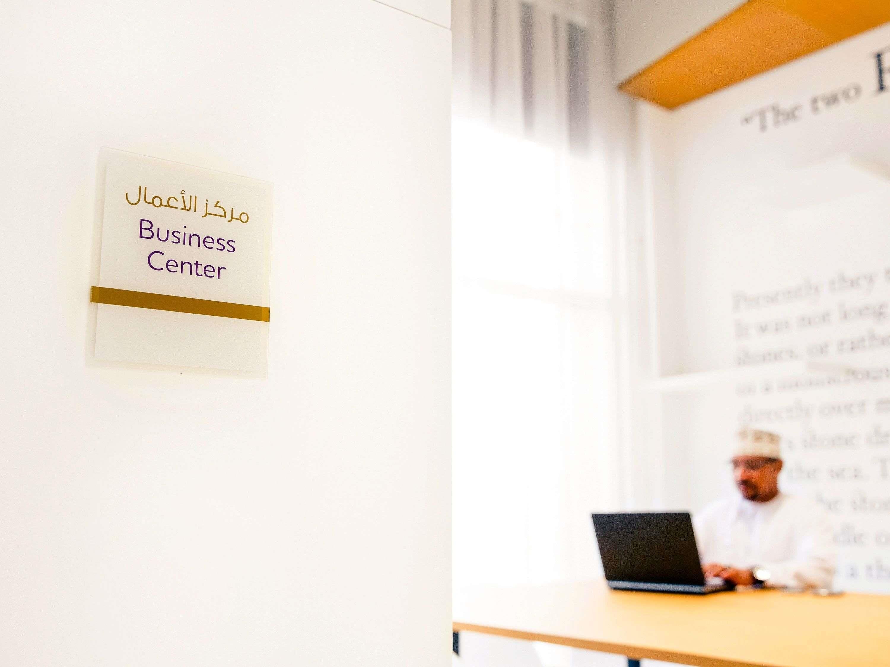 A sign with Arabic text and the English translation 'Business Center' on a wall.