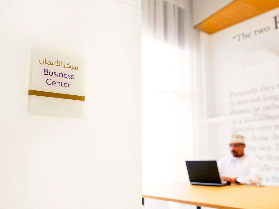 A sign with Arabic text and the English translation 'Business Center' on a wall.