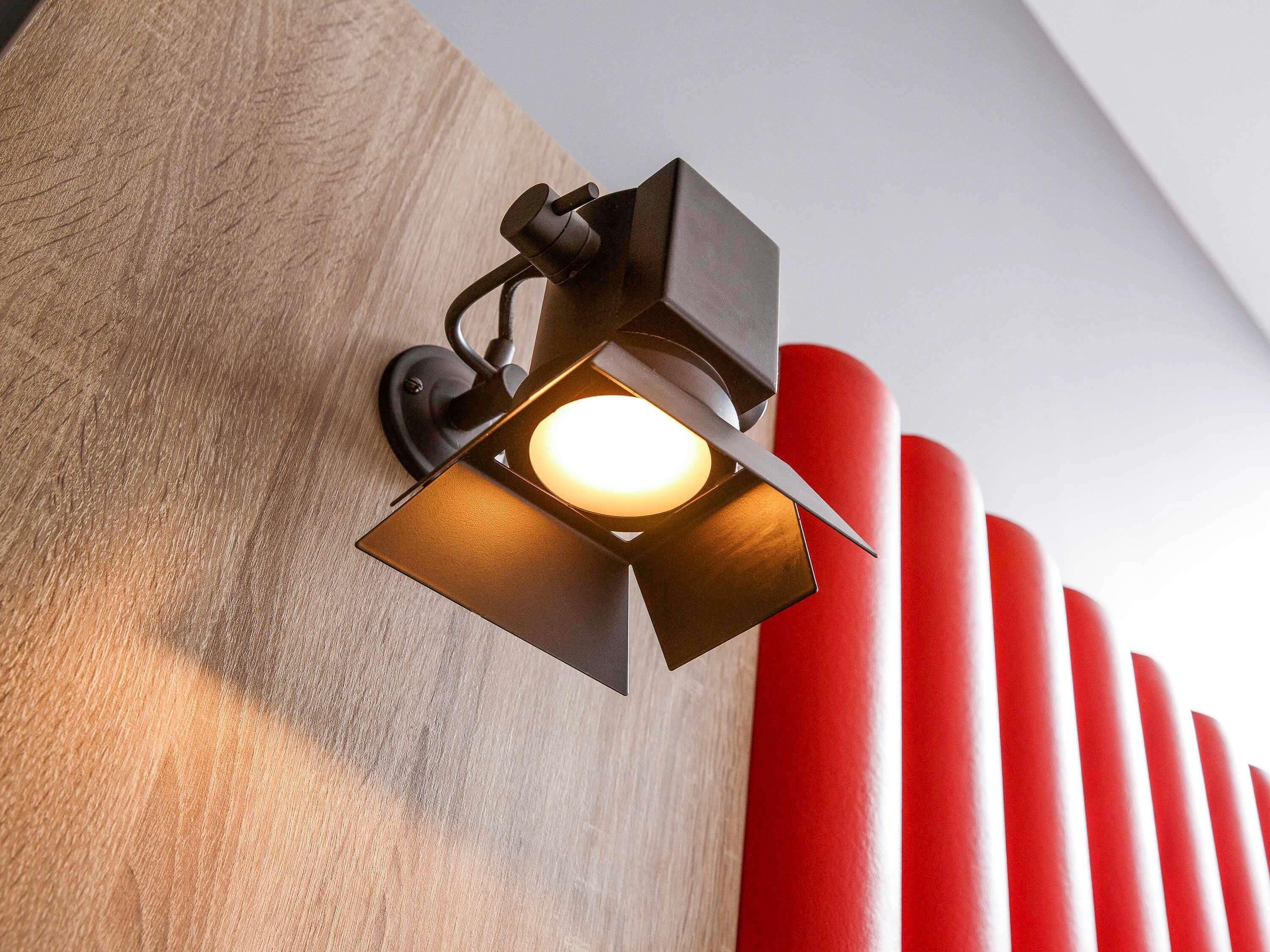 A wall-mounted light fixture with a square design and a visible bulb.