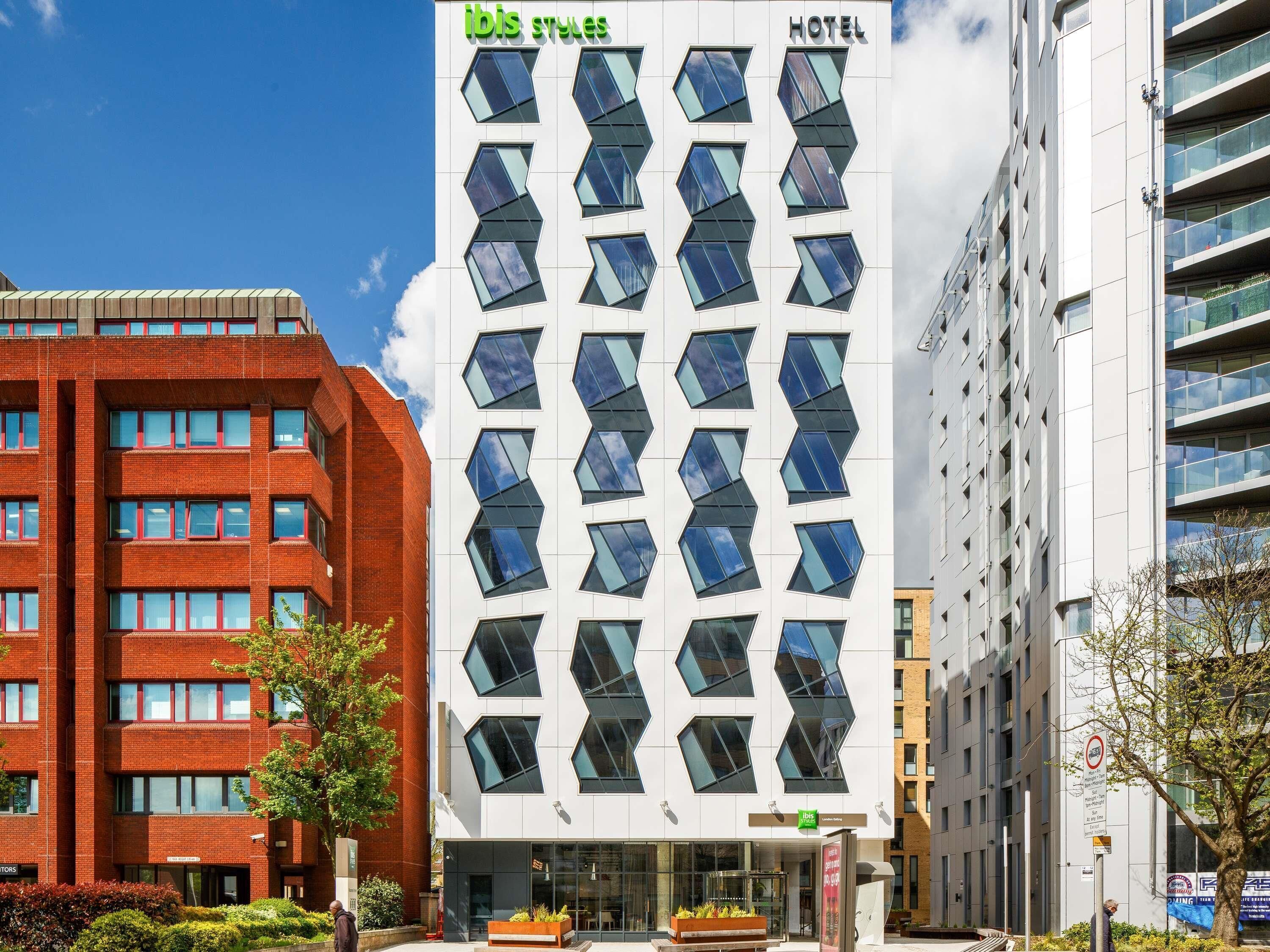 Een modern hotel met een opvallende geometrische gevel, meerdere ramen en een heldere lucht.