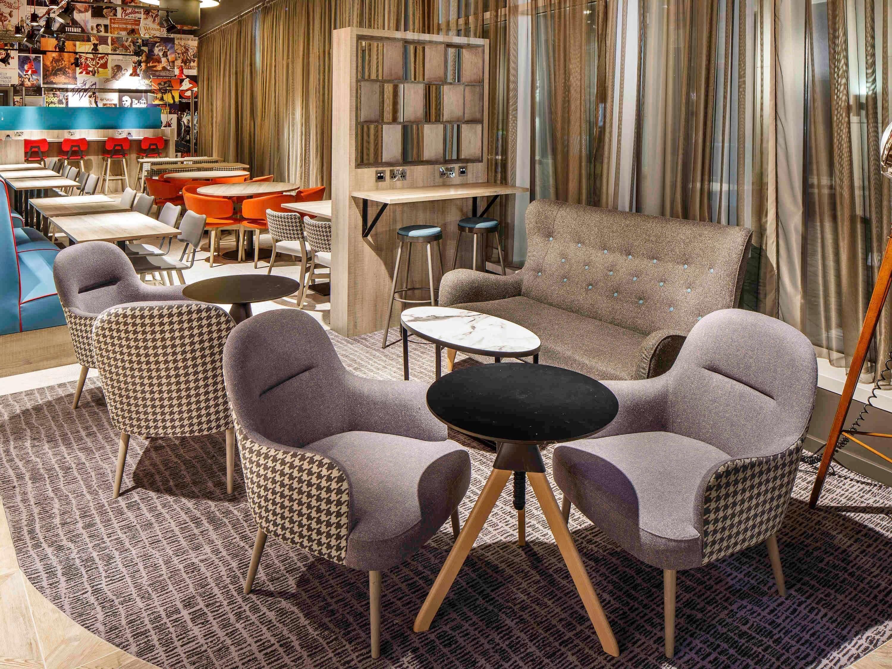 Un rincón de sala acogedor con sillones de estampado pata de gallo, un sofá capitonado y una mesa de centro de mármol.
