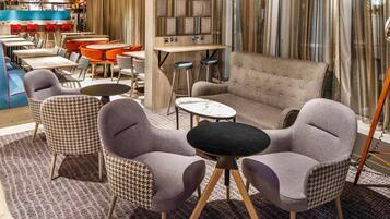 Un coin salon accueillant avec des fauteuils à motifs pied-de-poule, un canapé capitonné et une table basse en marbre.