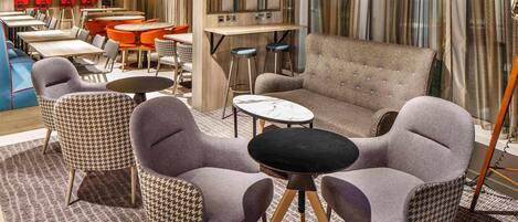 Un rincón de sala acogedor con sillones de estampado pata de gallo, un sofá capitonado y una mesa de centro de mármol.