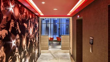 A modern hallway with a large photo mural, a seating area with chairs, and a fire safety sign on the wall.