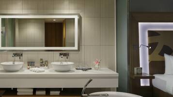 A modern bathroom with two sinks, a large mirror, and a bathtub.
