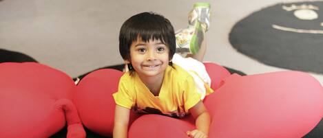 A child lying on red bean bags in a room with a carpeted floor.