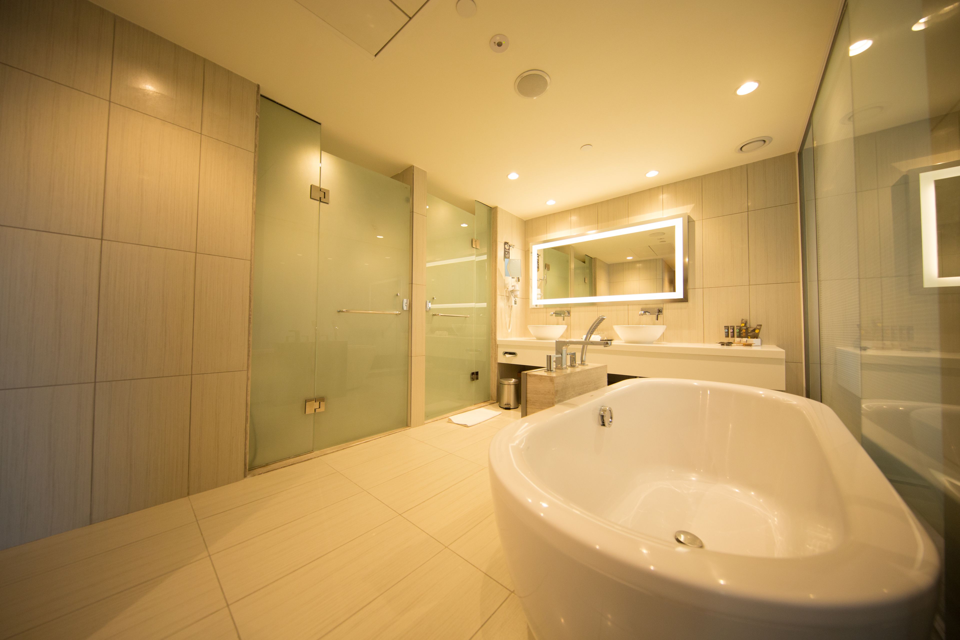 A modern bathroom with a freestanding bathtub, a glass-enclosed shower, and a large mirror above the sink.