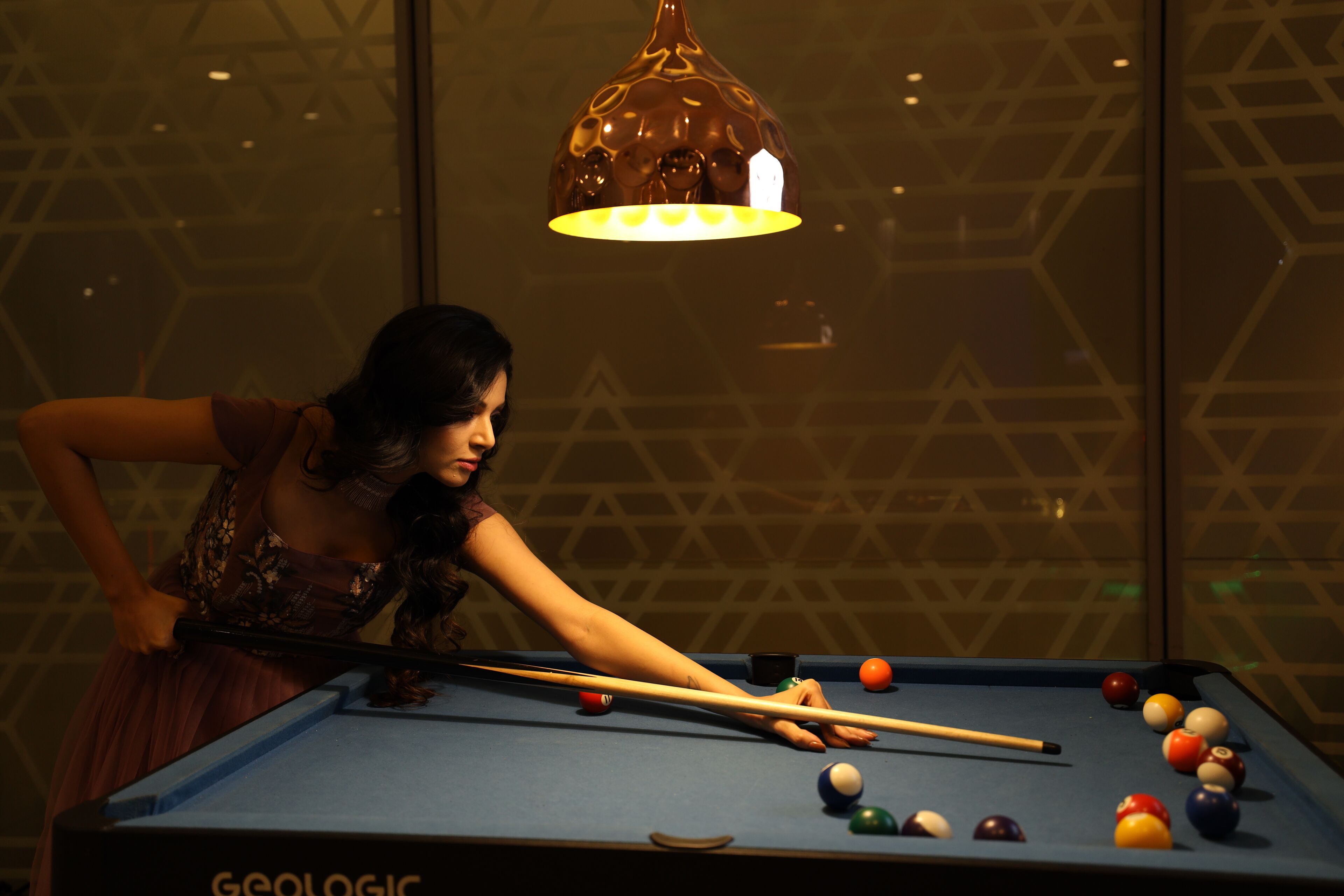 A pool table with balls, a pool cue, and a person playing.