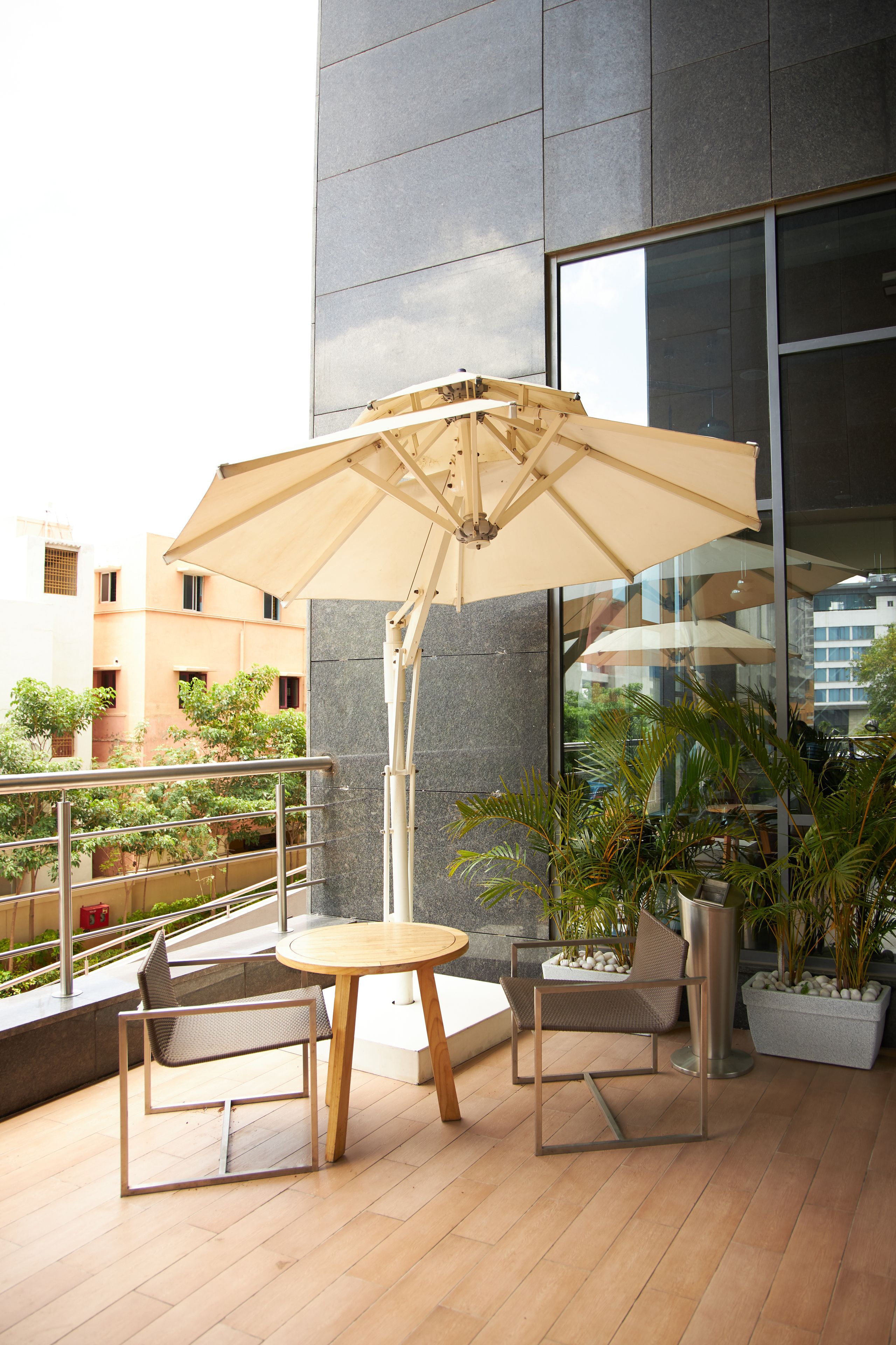 An outdoor seating area with a table and chairs, an umbrella, and potted plants.