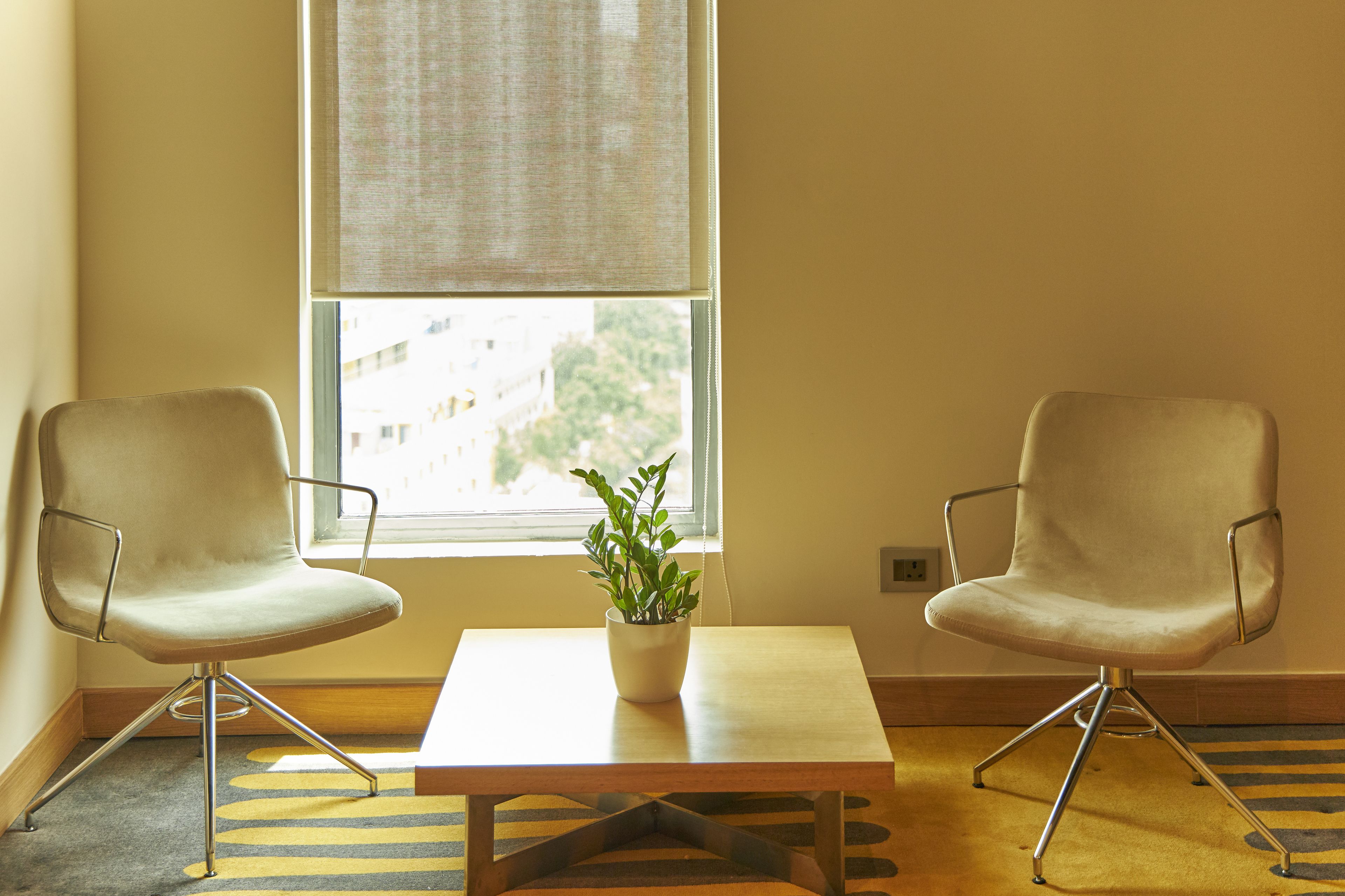 A room with two white chairs, a small table, and a potted plant.