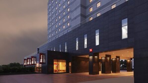 Un edificio de hotel moderno con varios pisos, grandes ventanales y una entrada destacada con un letrero.