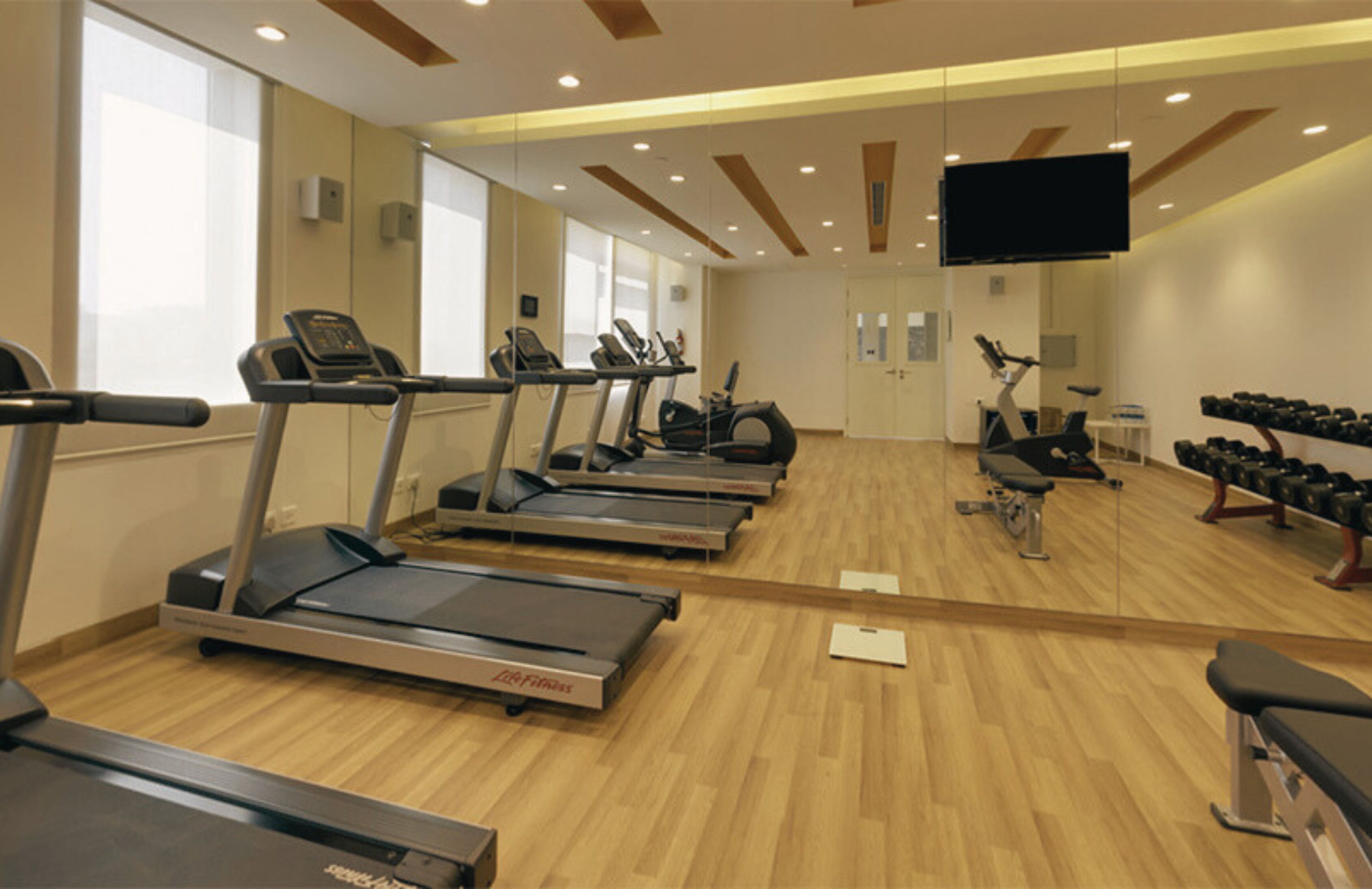 Une salle de sport équipée de tapis de course, de vélos elliptiques et de poids libres.