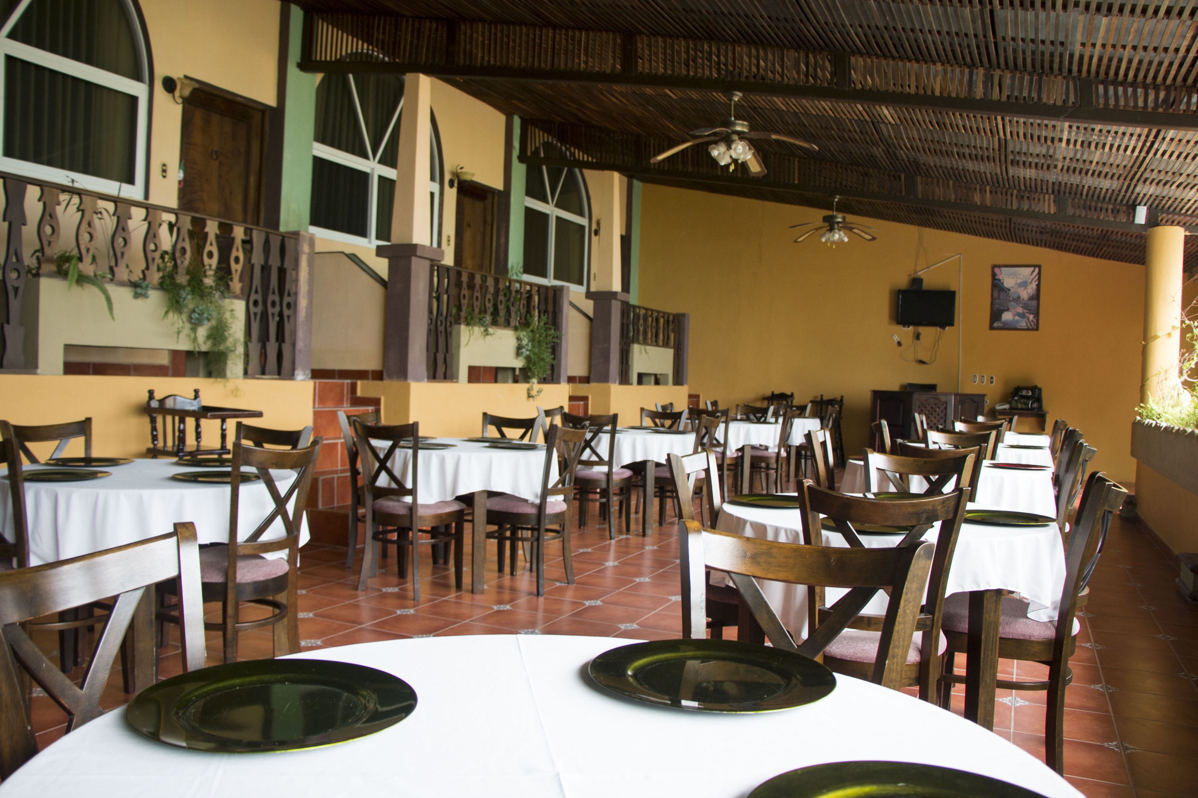 A restaurant with multiple tables and chairs, a tiled floor, and a ceiling fan.
