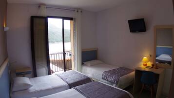 Une chambre d’hôtel avec deux lits, un bureau avec une chaise, une télévision et un balcon avec vue.