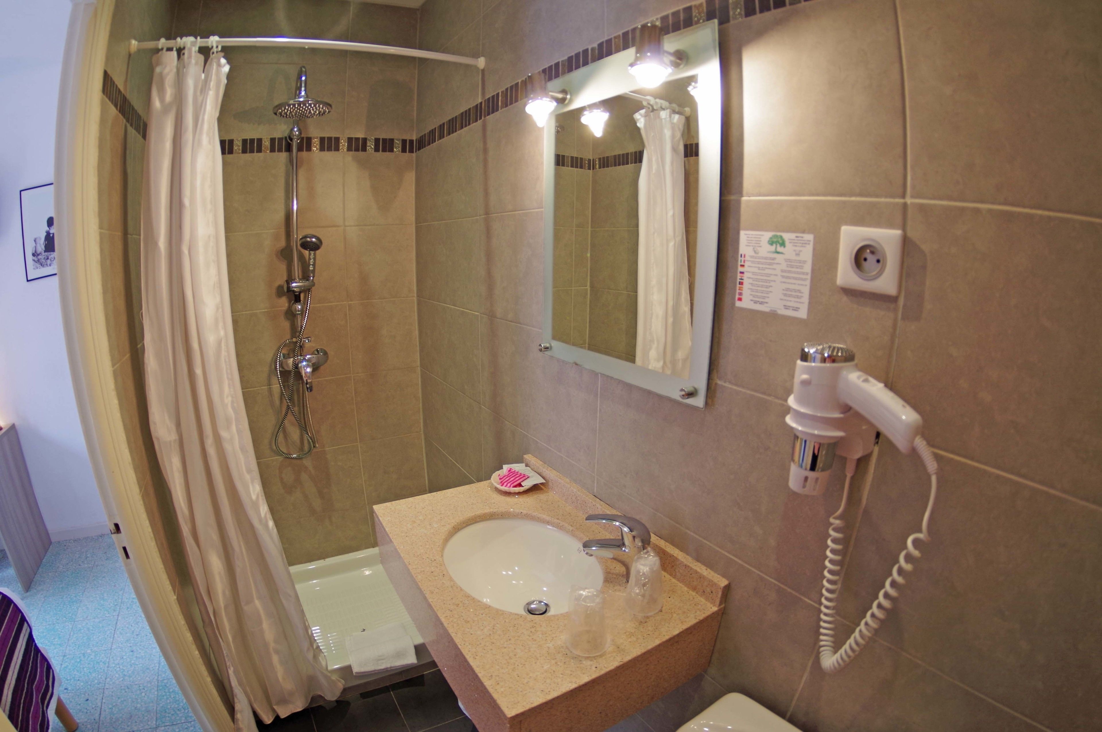 A bathroom with a shower, a sink, and a hairdryer.