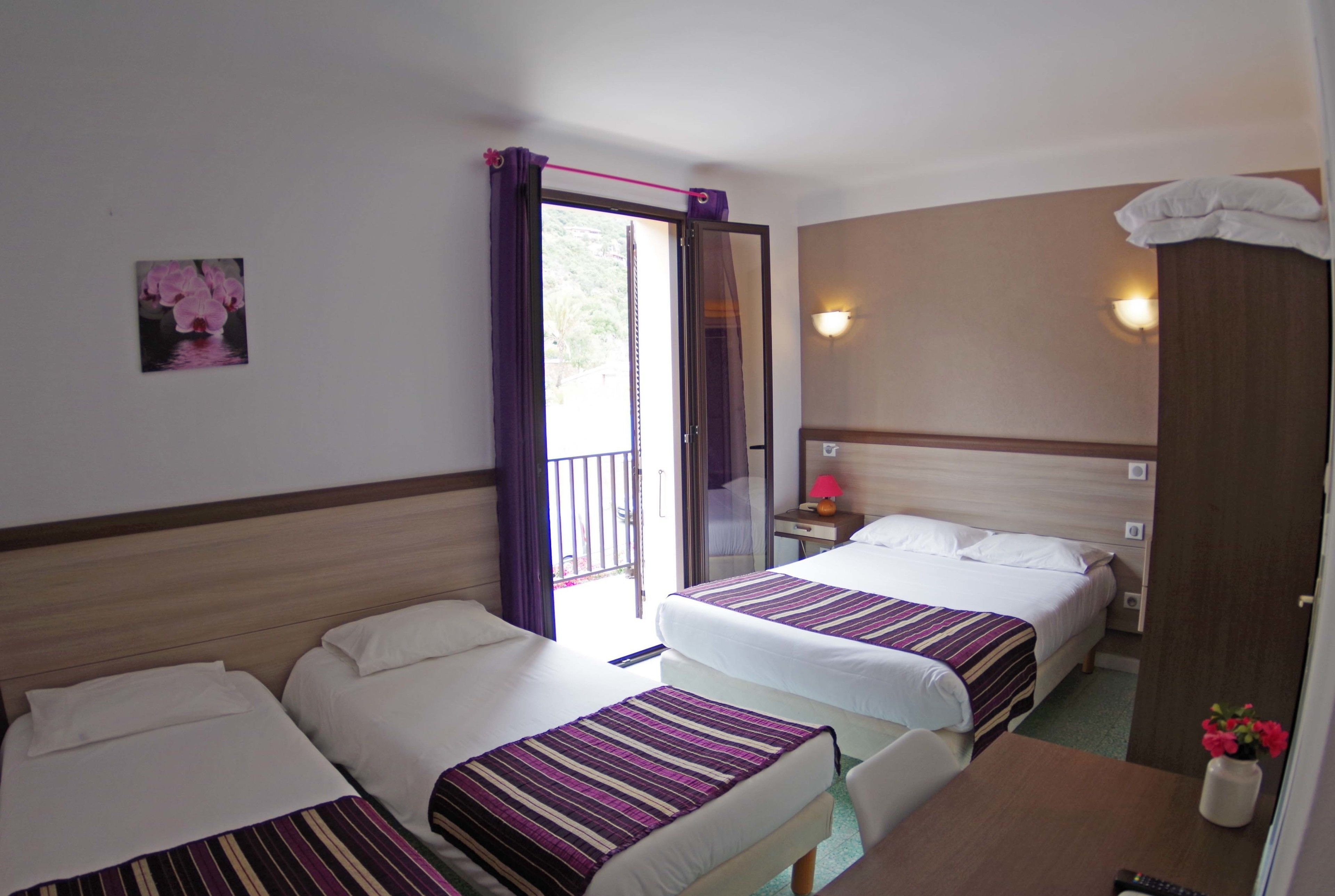 Une chambre d’hôtel avec deux lits, une petite table, une table de chevet et une porte de salle de bain.