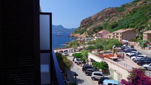 A coastal town with a view of the sea, parked cars, and buildings along the street.
