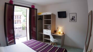 A bedroom with a bed, a desk, a chair, a wardrobe, a TV, and a balcony.