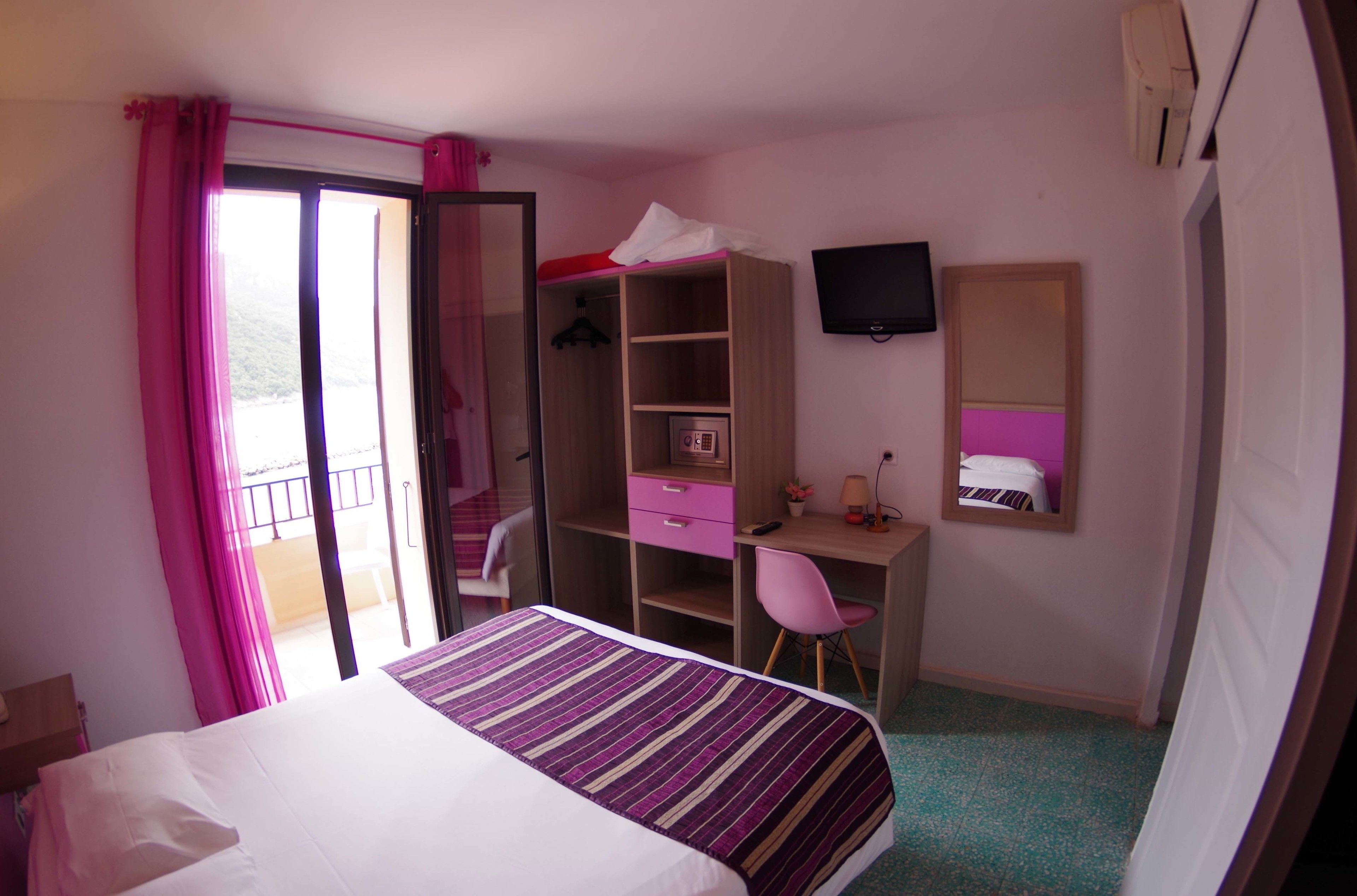 A bedroom with a bed, a desk, a chair, a wardrobe, and a TV.