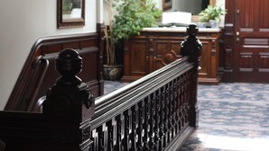 A grand staircase with ornate balusters and a polished wooden handrail. - Victorian Inn (Ferndale)