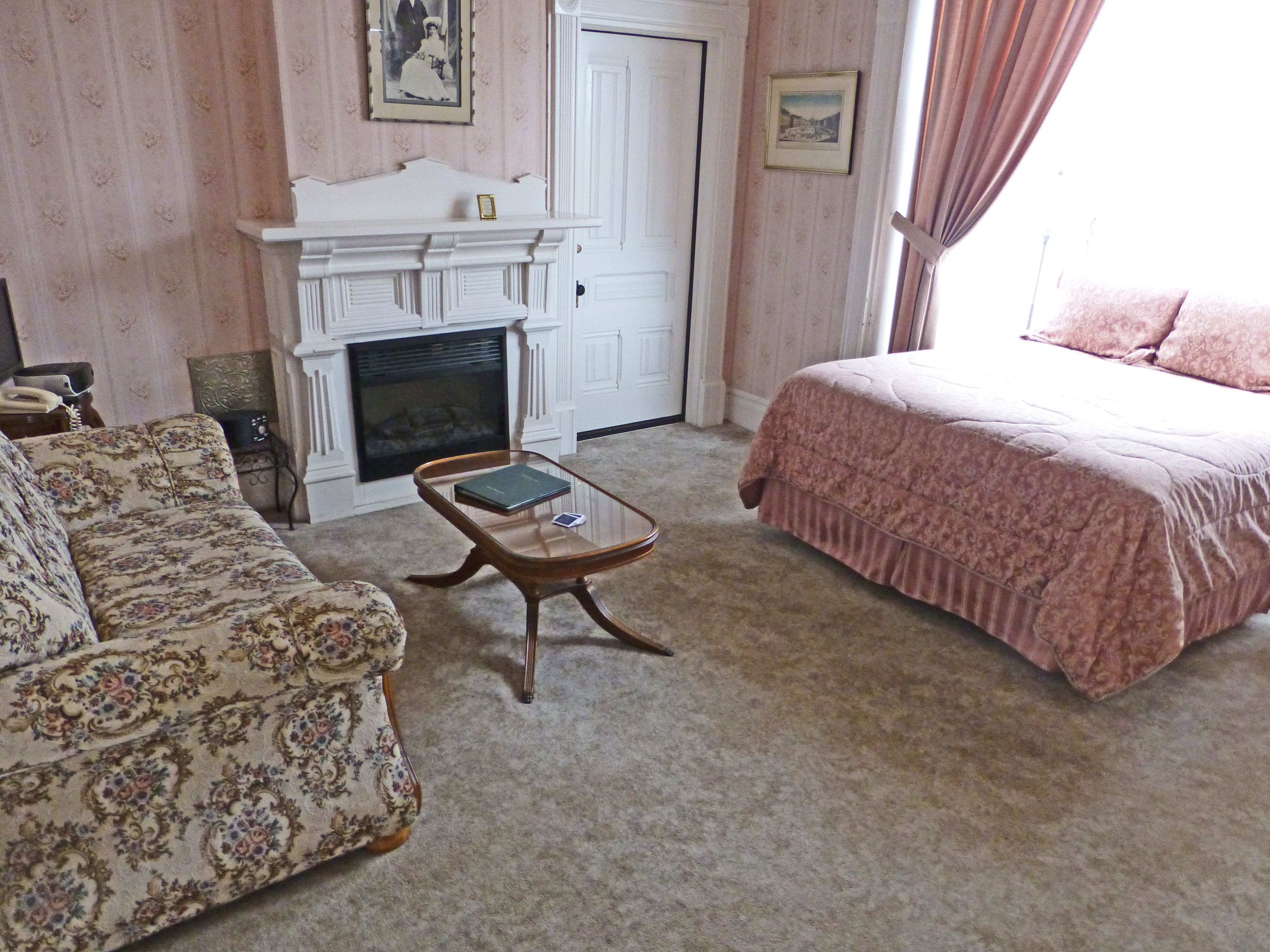 A room with a fireplace, a sofa, a bed, and a small table.