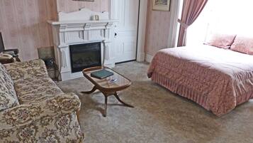 A room with a fireplace, a sofa, a bed, and a small table.