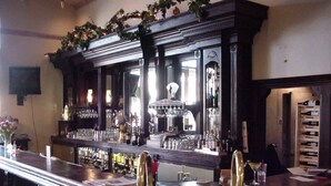 A bar area with a long counter, stools, and a variety of bottles and glasses. - Victorian Inn (Ferndale)