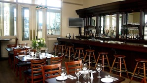 A restaurant with wooden tables and chairs, a bar area with stools, and a large mirror above the bar. - Victorian Inn (Ferndale)