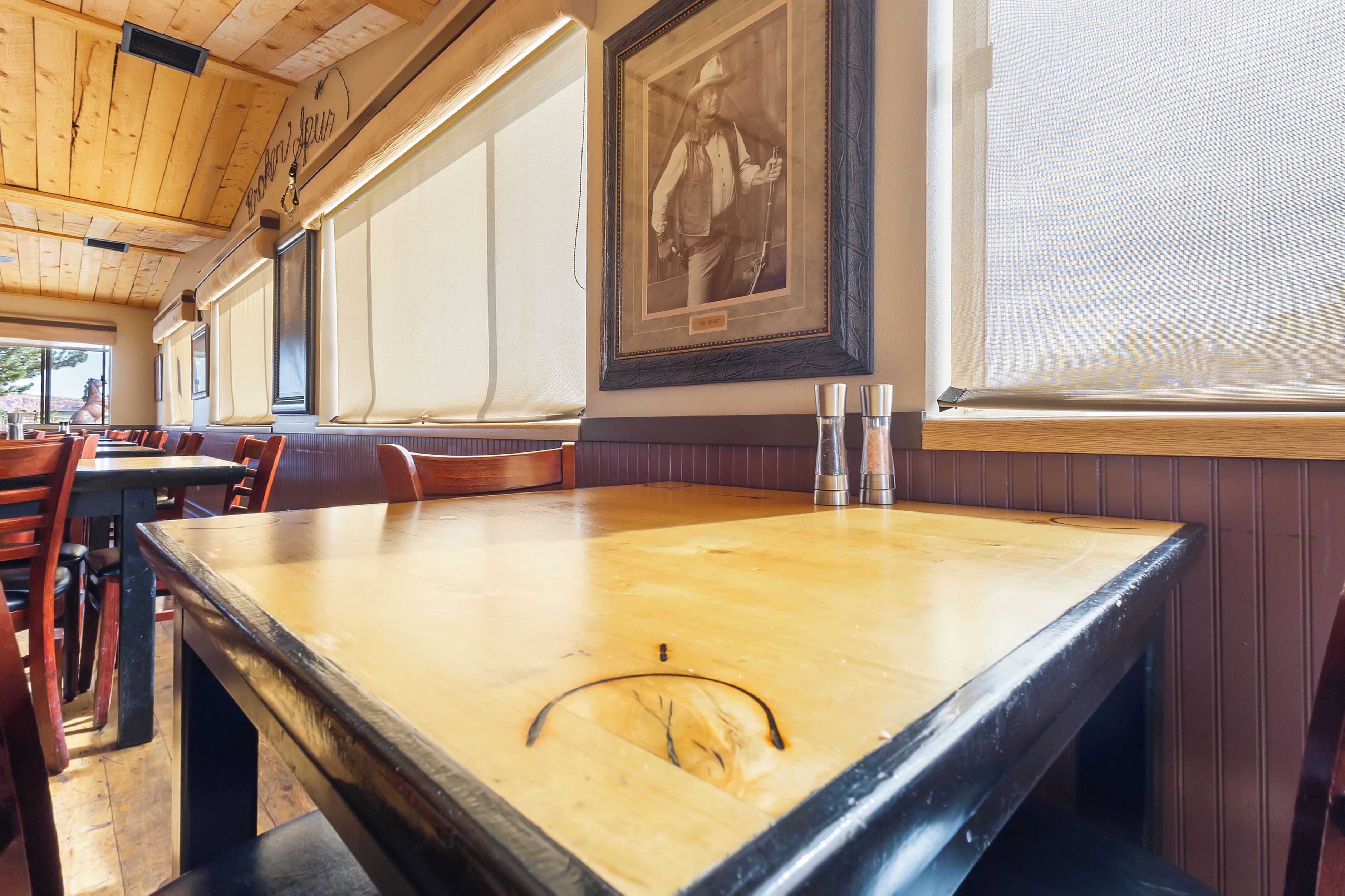 A restaurant interior with wooden tables, chairs, and a framed historical photograph on the wall.