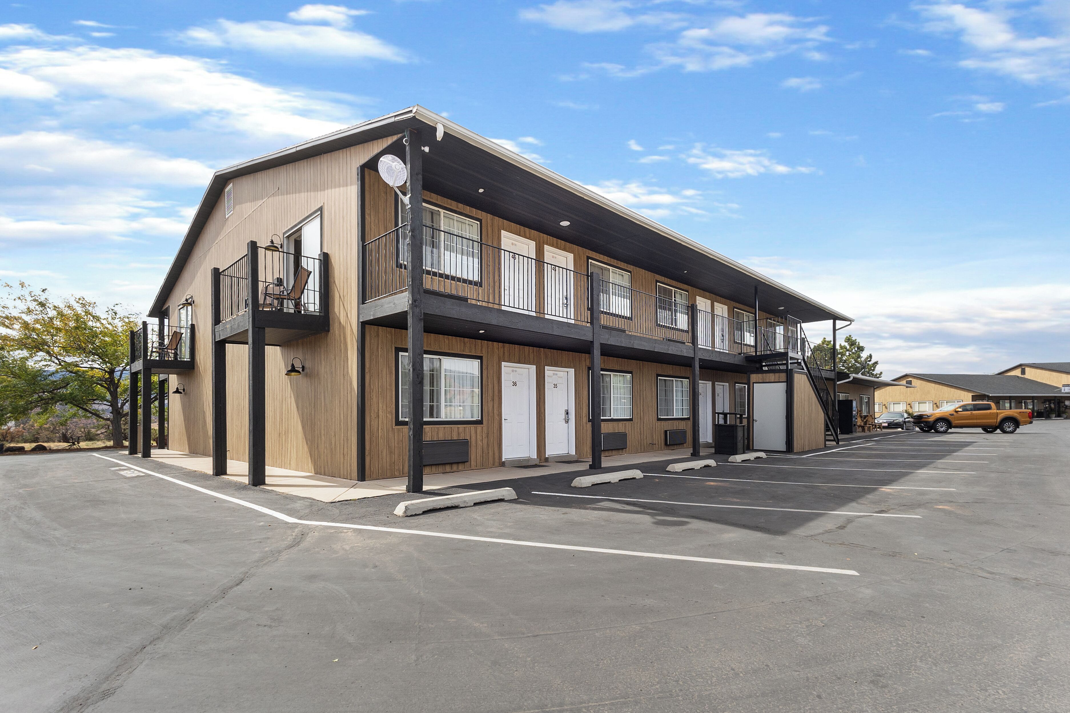 Um hotel com vários andares, design moderno, com varandas, estacionamento e céu claro.