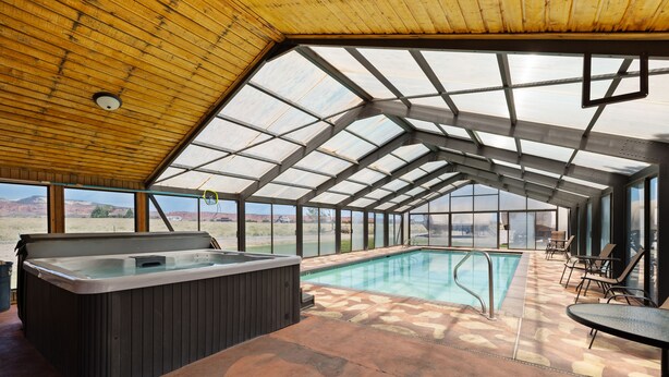 Piscina exterior coberta com hidromassagem, deck de madeira e amplas janelas com vista para a paisagem.