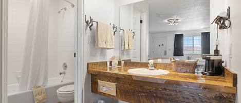 A bathroom with a wooden vanity, white sink, and a large mirror.
