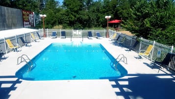 Una piscina al aire libre, sillones reclinables de piscina