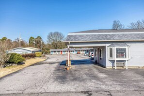 A motel with a parking lot, a covered area, and a row of rooms.
