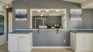A bathroom with a grey wall, a mirror, a ceiling fan, and two sinks.