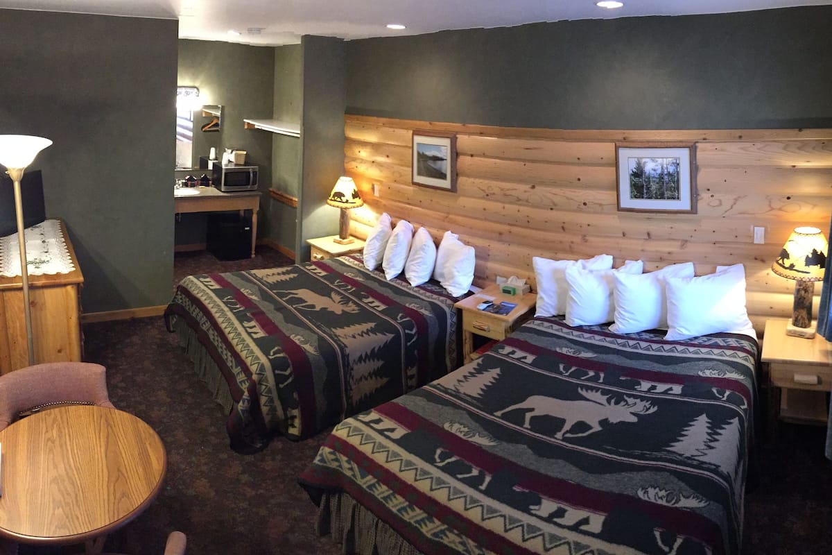 Una habitación de hotel con dos camas, un escritorio, una silla y una lámpara.