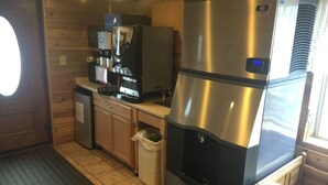 A compact kitchen with a stainless steel refrigerator, a coffee machine, and a small trash bin. - The Historic Madison Hotel Motel (West Yellowstone)