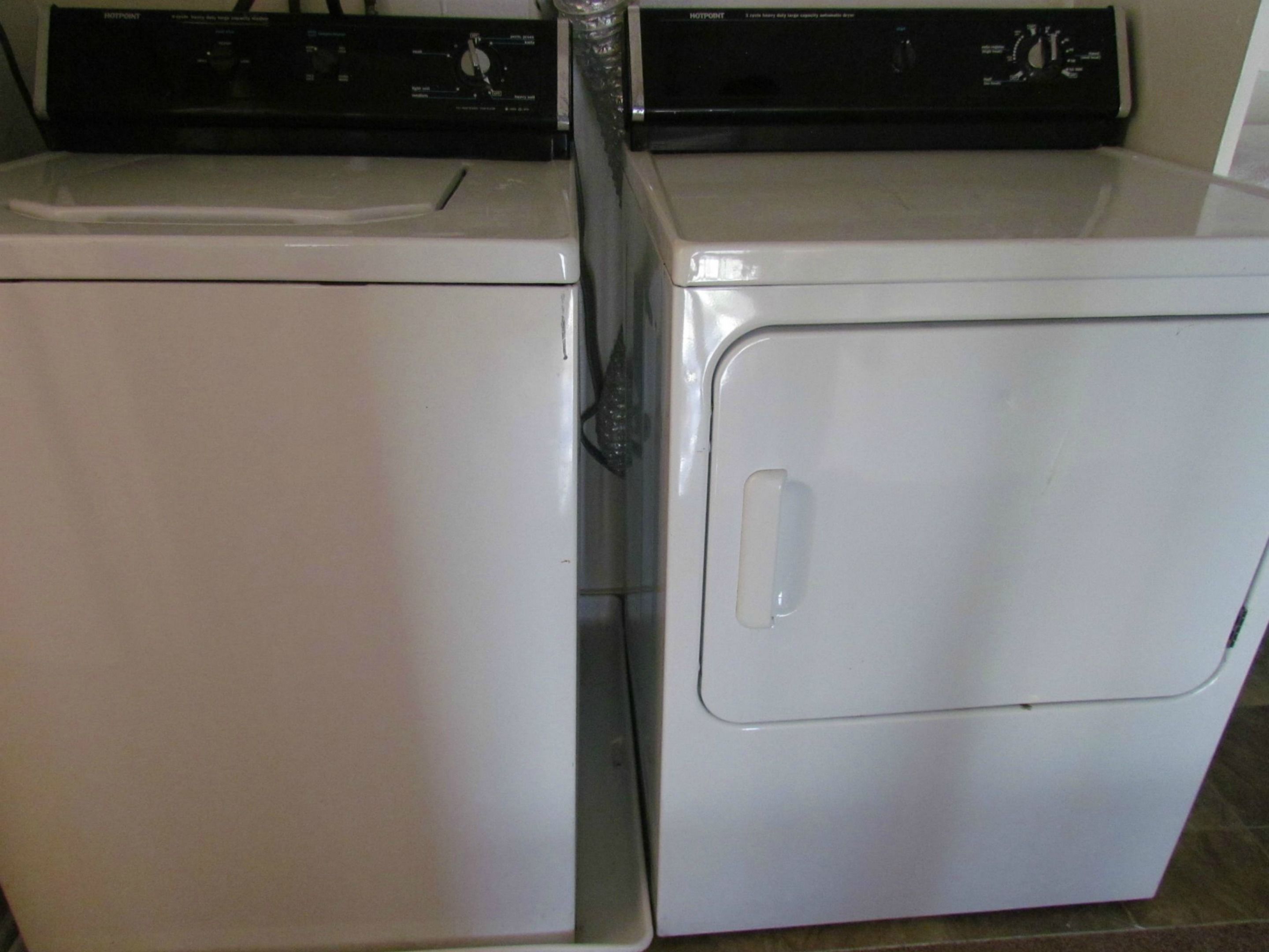 A compact, white laundry room with two stacked washing machines and a dryer.
