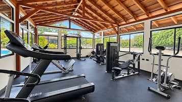 Un gimnasio con cintas de correr, máquinas de pesas y un ventilador de techo.