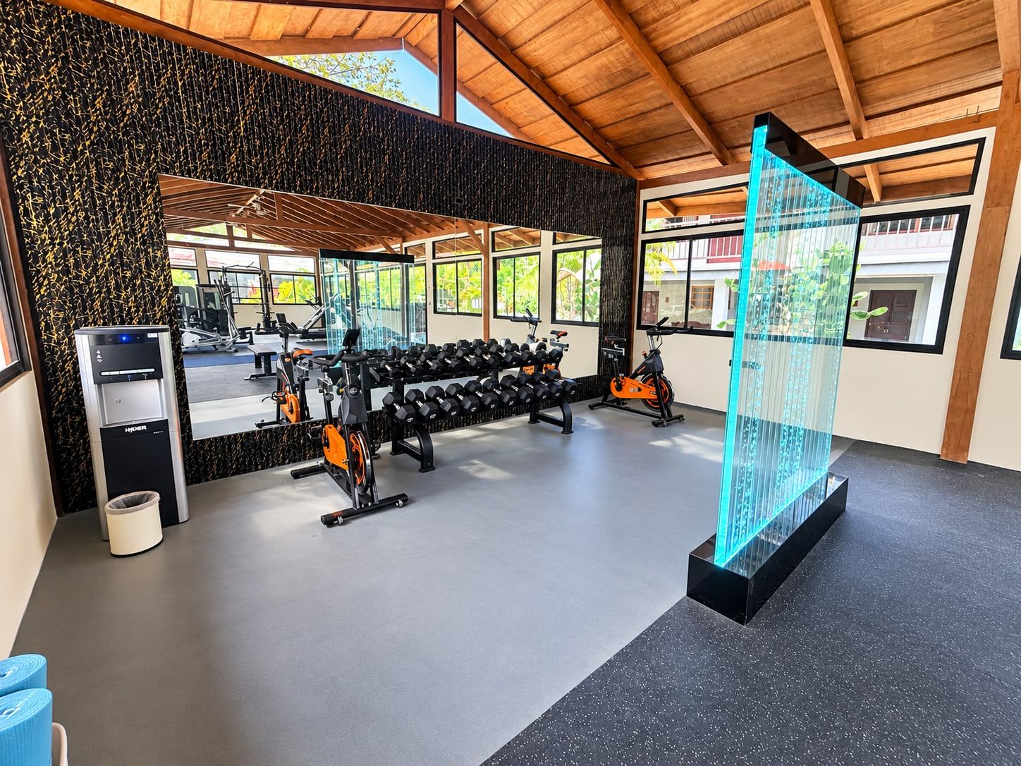 Een sportschool met trainingsapparatuur, een waterfontein en een groot raam.