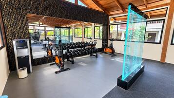 Een sportschool met trainingsapparatuur, een waterfontein en een groot raam.