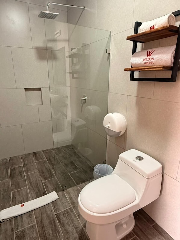 Un baño moderno con ducha de vidrio, inodoro y secador de manos.