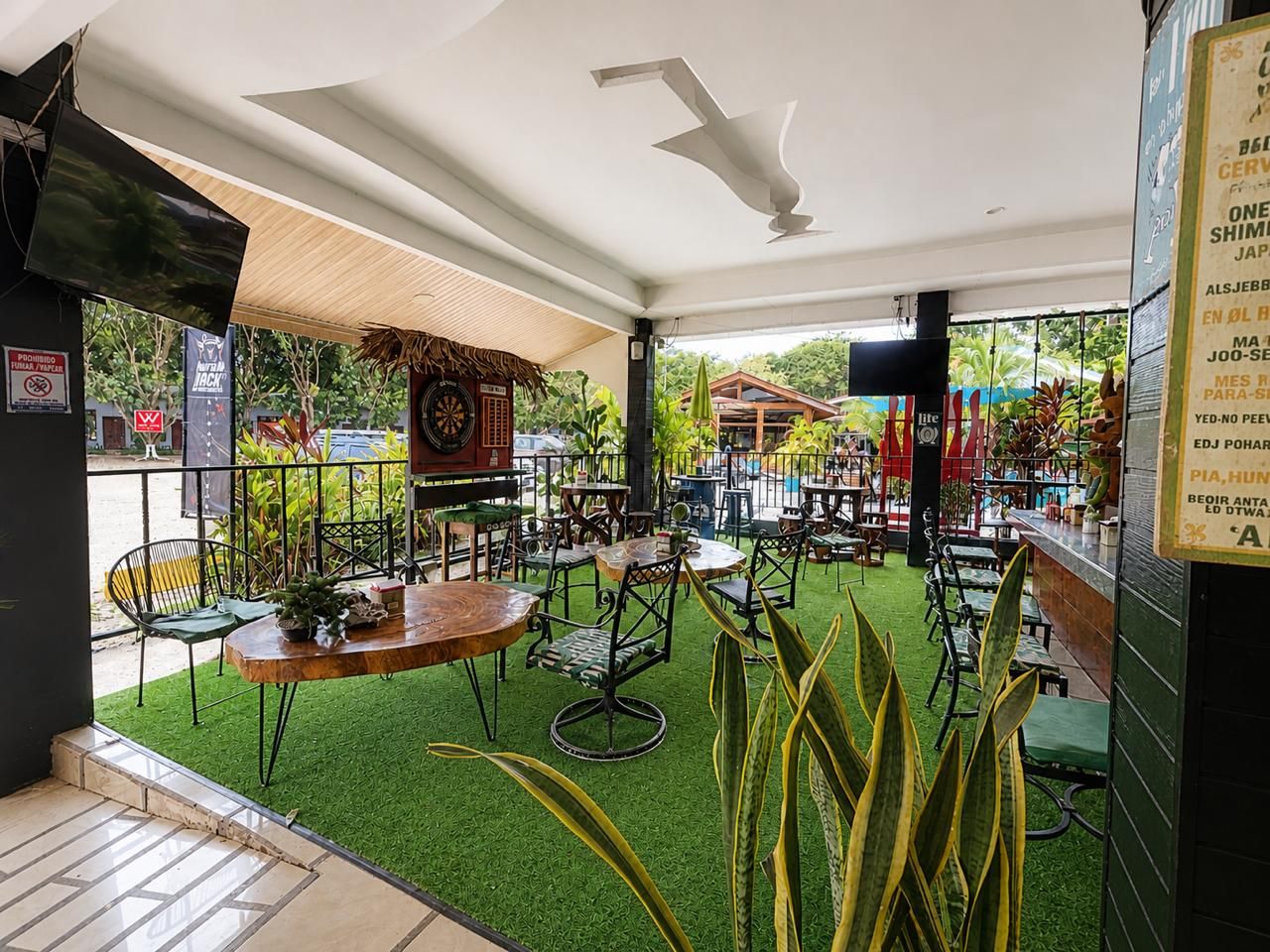 An indoor dining area with tables and chairs, a bar counter, and a green artificial turf floor.